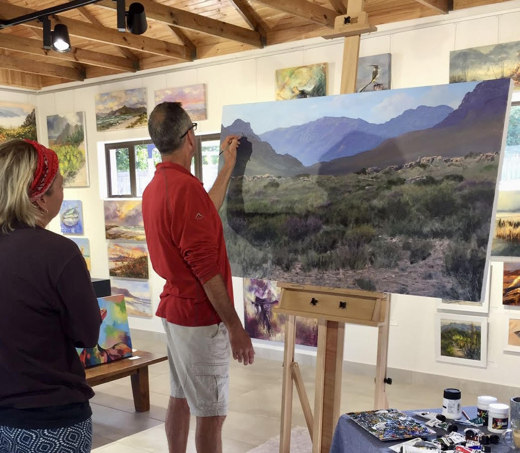 Landscape artist Andrew Cooper painting a fynbos mountain scene at Noordhoek Art Point